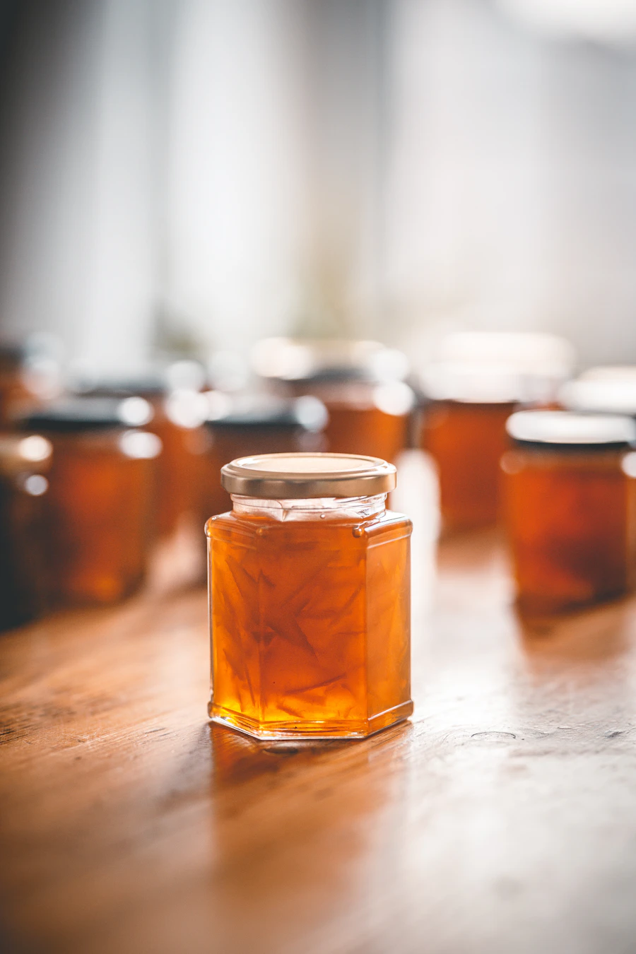 Amber marmalade jars on a wooden shelf, warm natural light